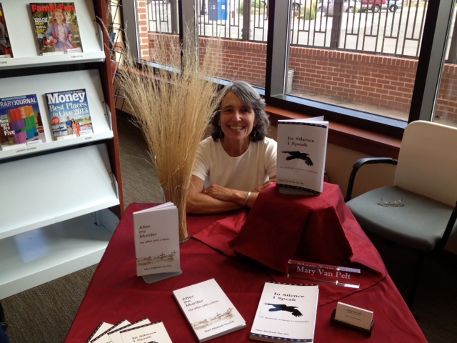 mary sits at book-signing table with display of her books